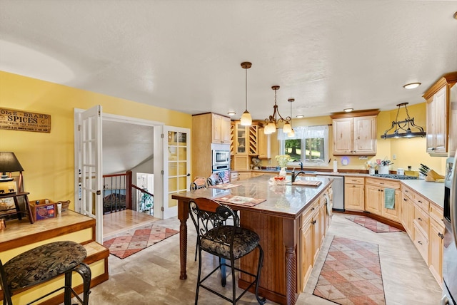 6350 S Meadowwood Ln, Missoula, MT 59803 - kitchen featuring light brown cabinets, a breakfast bar area, a kitchen island with sink, hanging light fixtures, and stainless steel appliances