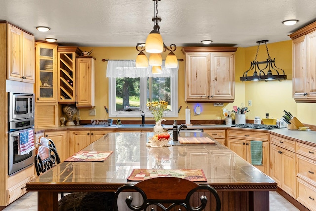 6350 S Meadowwood Ln, Missoula, MT 59803 - kitchen with appliances with stainless steel finishes, decorative light fixtures, a kitchen bar, a center island with sink, and glass insert cabinets