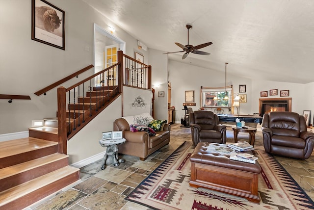 6350 S Meadowwood Ln, Missoula, MT 59803 - living area featuring vaulted ceiling, stone tile floors, ceiling fan, stairs, and a glass covered fireplace