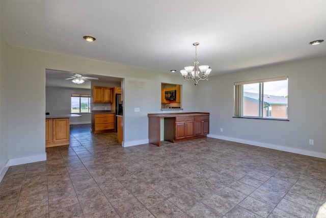 701 E Lewis St, East Helena, MT 59635 - kitchen featuring a chandelier, brown cabinetry, pendant lighting, black microwave, and a ceiling fan