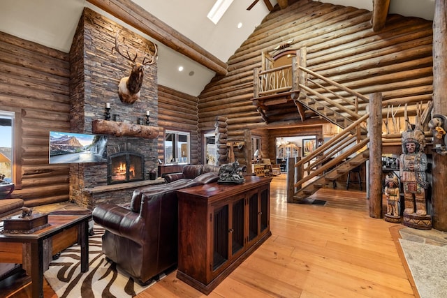 4475 Star Meadows Rd, Whitefish, MT 59937 - living room featuring high vaulted ceiling, a stone fireplace, rustic walls, stairs, and light wood-style flooring