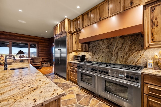 4475 Star Meadows Rd, Whitefish, MT 59937 - kitchen featuring high quality appliances, under cabinet range hood, rustic walls, brown cabinets, and decorative backsplash