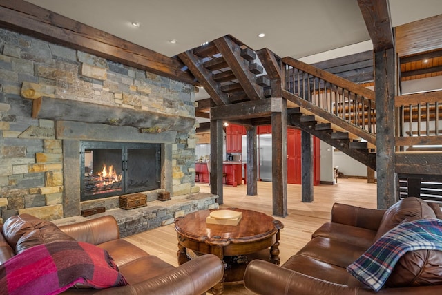 4475 Star Meadows Rd, Whitefish, MT 59937 - living area featuring wood finished floors, a stone fireplace, stairway, a towering ceiling, and beam ceiling