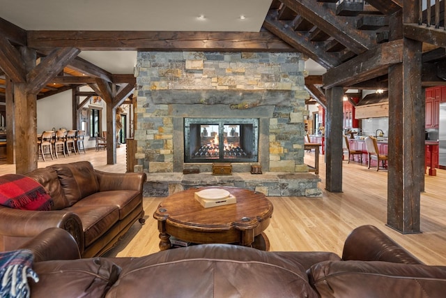 4475 Star Meadows Rd, Whitefish, MT 59937 - living room featuring wood finished floors, a stone fireplace, and beamed ceiling