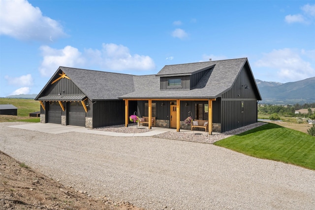 559 Stage Springs Ln, Stevensville, MT 59870 - modern farmhouse featuring stone siding, covered porch, an attached garage, concrete driveway, and a mountain view