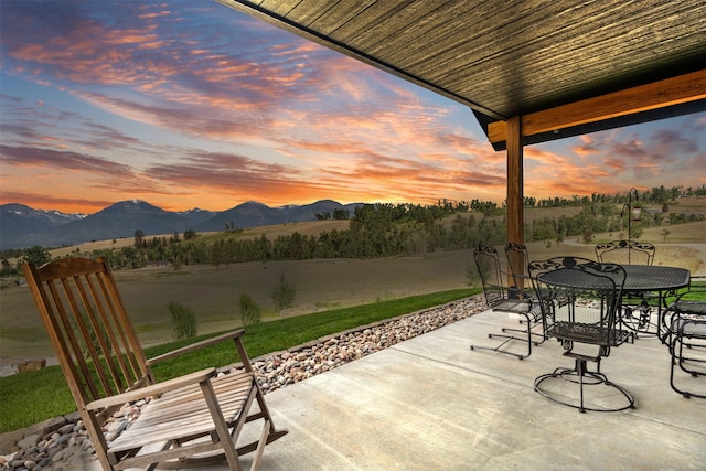 559 Stage Springs Ln, Stevensville, MT 59870 - patio terrace at dusk with a patio area, a mountain view, outdoor dining area, and a lawn