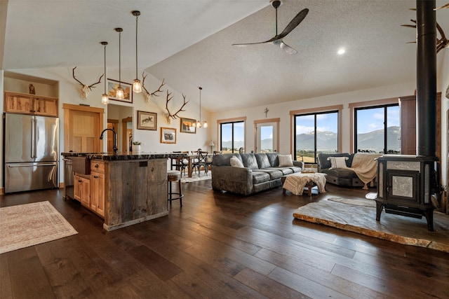 559 Stage Springs Ln, Stevensville, MT 59870 - living area with a wood stove, a ceiling fan, dark wood-style floors, high vaulted ceiling, and a textured ceiling