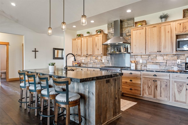 559 Stage Springs Ln, Stevensville, MT 59870 - kitchen featuring wall chimney range hood, stainless steel microwave, light brown cabinets, lofted ceiling, and dark wood-style flooring