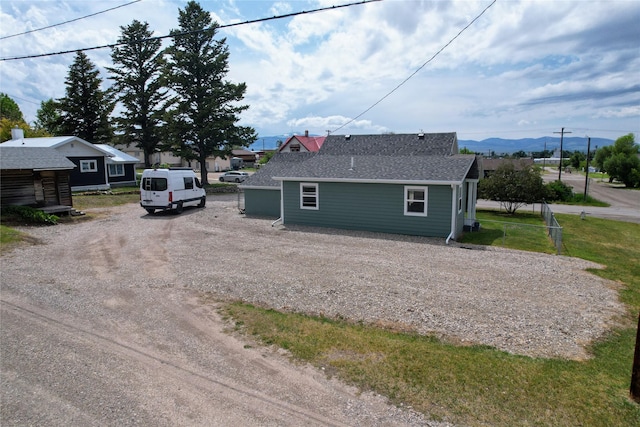 102 E Chilton St, White Sulphur Springs, MT 59645 - view of home's exterior with dirt driveway, a mountain view, and a shingled roof