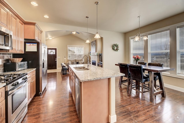 2871 Alexis Ave, Helena, MT 59601 - kitchen with stainless steel appliances, dark wood-style flooring, vaulted ceiling, light stone countertops, and a kitchen island with sink