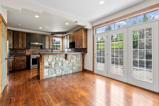 54 Bluebird Dr, Kalispell, MT 59901 - kitchen featuring under cabinet range hood, stainless steel range with gas stovetop, hardwood / wood-style flooring, recessed lighting, and tasteful backsplash