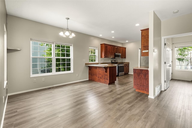 603 Luella Ln, Missoula, MT 59801 - kitchen with stainless steel appliances, a peninsula, a breakfast bar area, recessed lighting, and light wood-style flooring