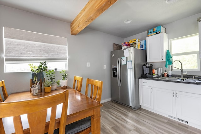 3265 US Highway 2 W, Kalispell, MT 59901 - kitchen with stainless steel refrigerator with ice dispenser, dark countertops, healthy amount of natural light, light wood-type flooring, and beam ceiling