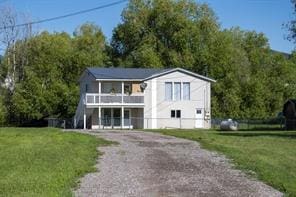 3265 US Highway 2 W, Kalispell, MT 59901 - view of front facade with a balcony, a front yard, and gravel driveway