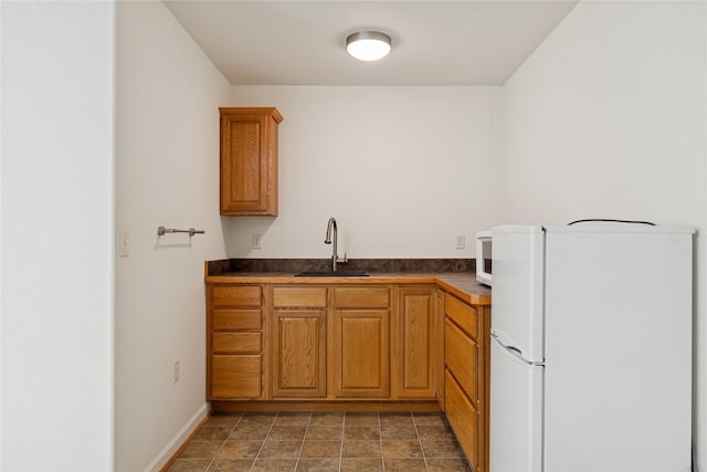 209 E Nicklaus Ave, Kalispell, MT 59901 - kitchen with freestanding refrigerator, dark countertops, and brown cabinetry