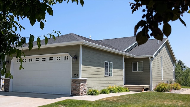 209 E Nicklaus Ave, Kalispell, MT 59901 - view of property exterior featuring concrete driveway, a garage, stone siding, a lawn, and roof with shingles
