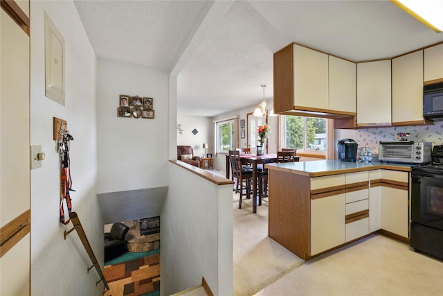 305 S Dell Dr, Havre, MT 59501 - kitchen with black appliances, a peninsula, light colored carpet, cream cabinets, and pendant lighting