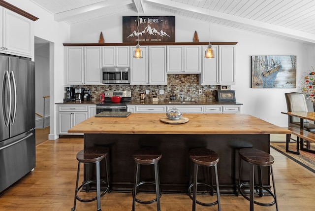9 Blue Stem Way, Three Forks, MT 59752 - kitchen with appliances with stainless steel finishes, butcher block countertops, light wood finished floors, a kitchen breakfast bar, and tasteful backsplash