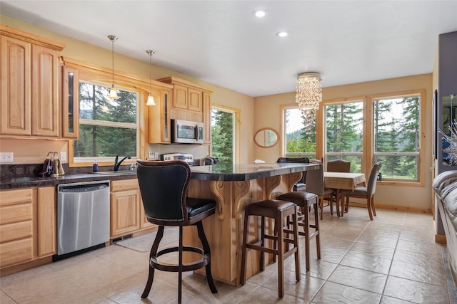 6611 Packer Creek Rd, Haugan, MT 59842 - kitchen with appliances with stainless steel finishes, light brown cabinetry, a breakfast bar, healthy amount of natural light, and recessed lighting
