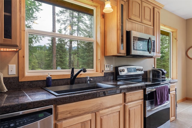 6611 Packer Creek Rd, Haugan, MT 59842 - kitchen with stainless steel appliances, glass insert cabinets, light tile patterned floors, and tile counters