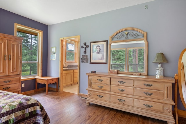 6611 Packer Creek Rd, Haugan, MT 59842 - bedroom featuring multiple windows, light wood-style floors, and connected bathroom