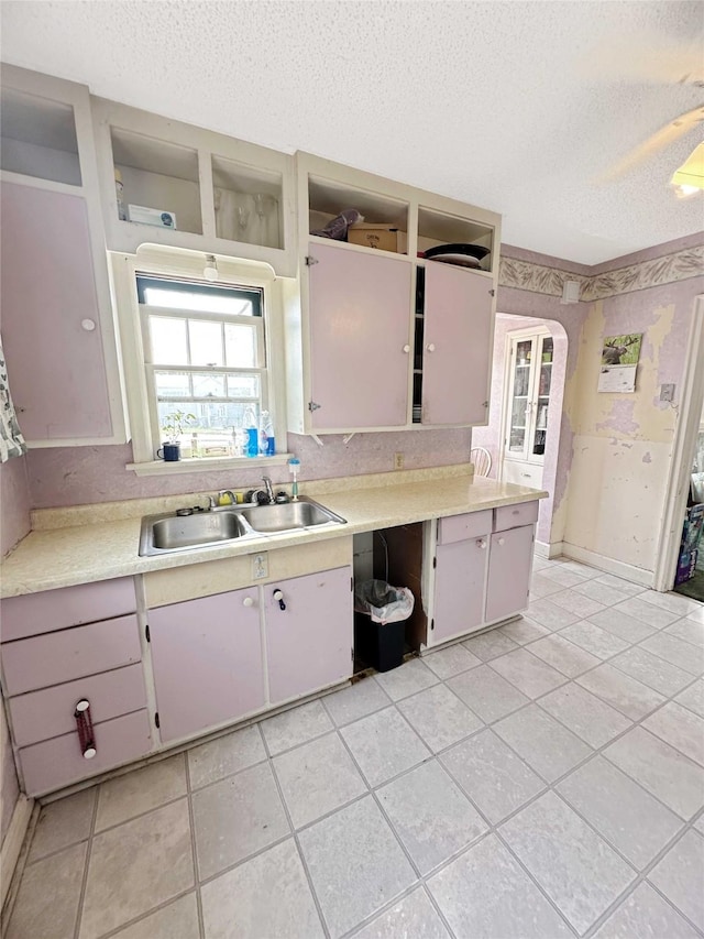 214 2nd Ave SW, Cut Bank, MT 59427 - kitchen with a textured ceiling, light countertops, open shelves, light tile patterned floors, and arched walkways