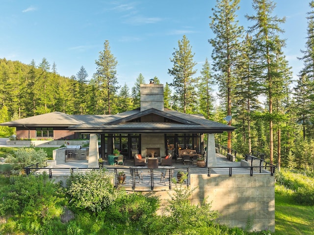 6601 Russian Joe Rd, Missoula, MT 59802 - rear view of property with exterior kitchen, a chimney, a view of trees, and a patio