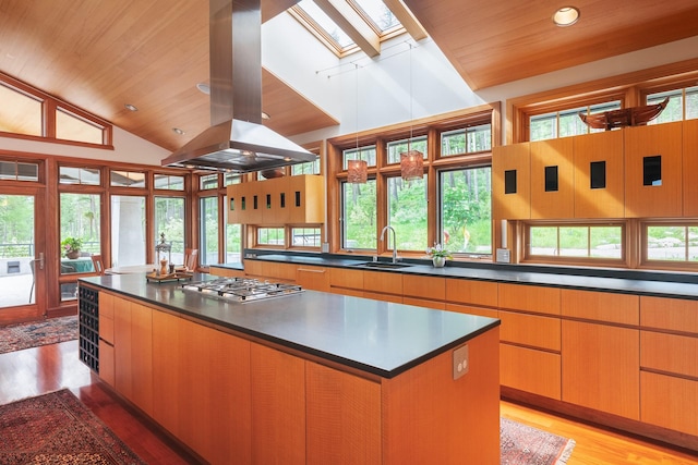 6601 Russian Joe Rd, Missoula, MT 59802 - kitchen featuring island exhaust hood, stainless steel gas stovetop, a skylight, wooden ceiling, and dark countertops