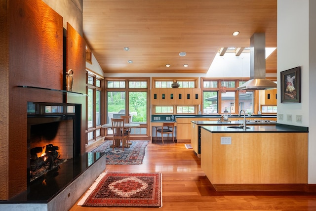 6601 Russian Joe Rd, Missoula, MT 59802 - kitchen with island range hood, light wood-style floors, dark countertops, a warm lit fireplace, and recessed lighting