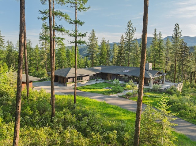 6601 Russian Joe Rd, Missoula, MT 59802 - view of front facade featuring a view of trees, driveway, a mountain view, and a chimney