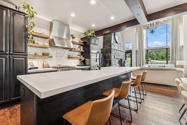 153 Slopeside Dr Unit 14, Whitefish, MT 59937 - kitchen with wall chimney exhaust hood, light countertops, backsplash, dark wood-style flooring, and beamed ceiling