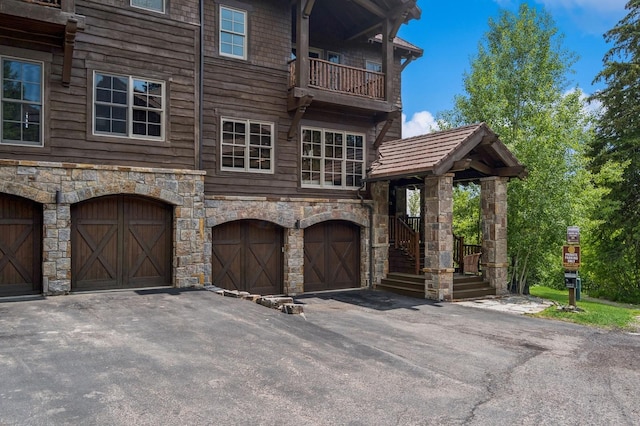 153 Slopeside Dr Unit 14, Whitefish, MT 59937 - view of front of property with an attached garage, stone siding, a balcony, and asphalt driveway