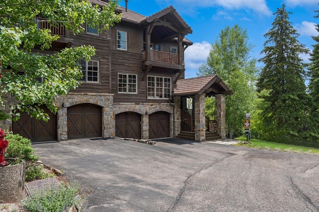 153 Slopeside Dr Unit 14, Whitefish, MT 59937 - view of front of home featuring a balcony, stone siding, a garage, and asphalt driveway