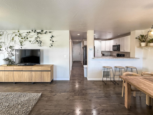 2876 Twilight Ave, Helena, MT 59601 - kitchen featuring black microwave, dark wood finished floors, white cabinetry, recessed lighting, and freestanding refrigerator