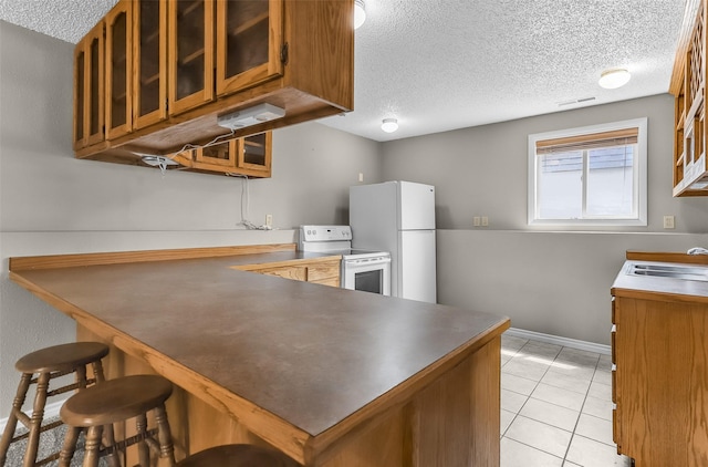 1312 2nd Ave NW, Great Falls, MT 59404 - kitchen with white appliances, brown cabinetry, a textured ceiling, a peninsula, and glass insert cabinets