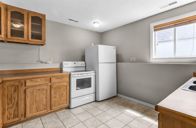 1312 2nd Ave NW, Great Falls, MT 59404 - kitchen with white appliances, brown cabinetry, light countertops, glass insert cabinets, and a textured ceiling
