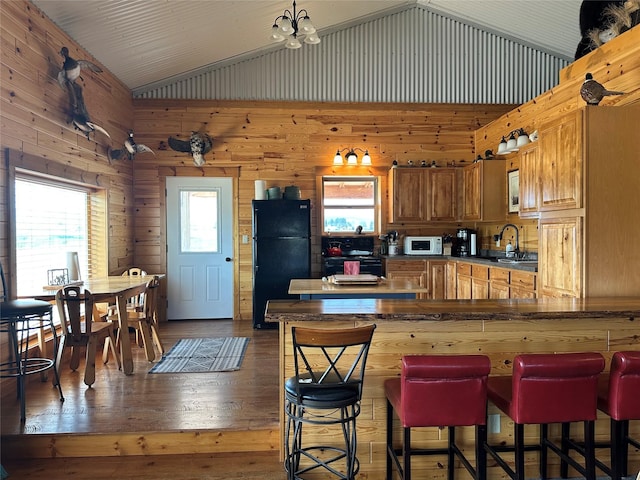 30 Kolbeck Ln, Hall, MT 59837 - kitchen featuring black appliances, vaulted ceiling, dark wood-style floors, a breakfast bar, and wooden walls