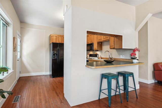 915 3rd St, Missoula, MT 59802 - kitchen featuring black appliances, dark wood finished floors, a breakfast bar area, and a peninsula