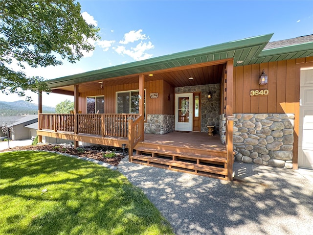 3640 Jack Dr, Missoula, MT 59803 - view of exterior entry with stone siding, a porch, a lawn, and board and batten siding