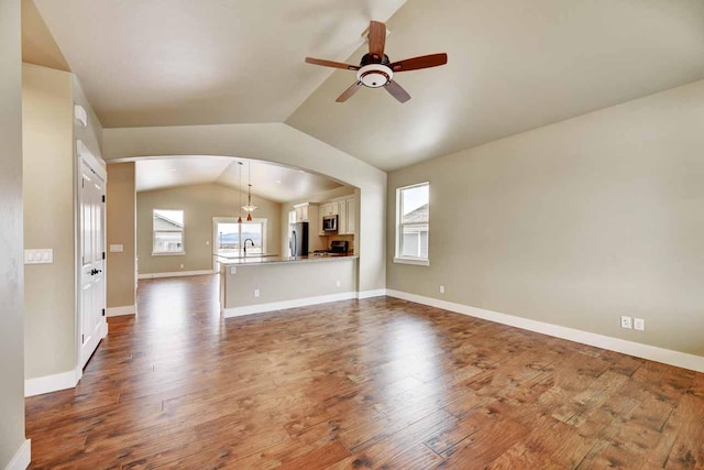 2909 Travis Ave, Helena, MT 59601 - unfurnished living room with a ceiling fan, healthy amount of natural light, lofted ceiling, arched walkways, and dark wood-type flooring