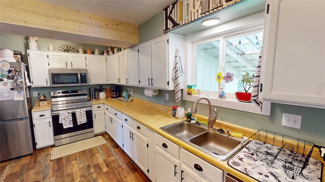181 Ridgeway Dr, Lolo, MT 59847 - kitchen featuring appliances with stainless steel finishes, white cabinetry, light countertops, dark wood-style flooring, and healthy amount of natural light