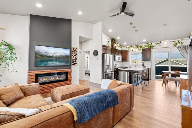 7070 Max Dr, Missoula, MT 59803 - living room featuring a ceiling fan, light wood-style flooring, a glass covered fireplace, high vaulted ceiling, and recessed lighting