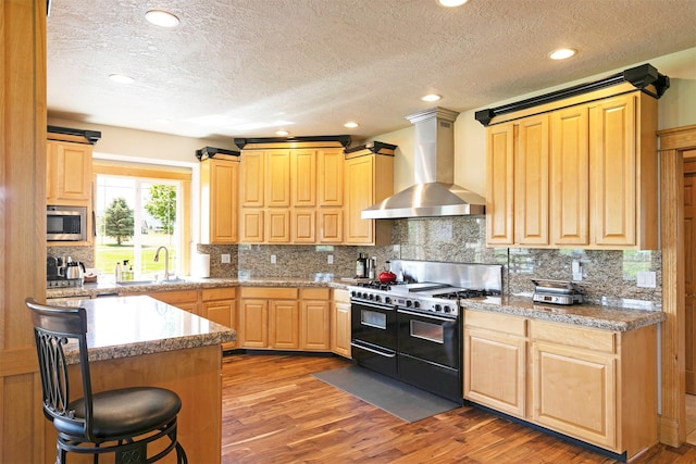 424 Saddle Ridge Rd, Hamilton, MT 59840 - kitchen with wall chimney range hood, double oven range, stainless steel microwave, light wood-style floors, and a textured ceiling
