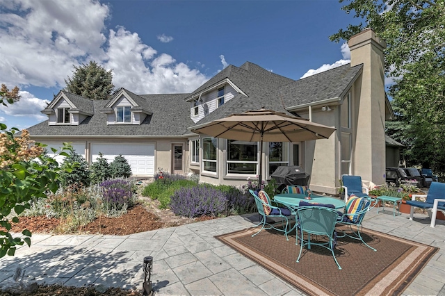 424 Saddle Ridge Rd, Hamilton, MT 59840 - back of house featuring stucco siding, a shingled roof, a patio area, an attached garage, and outdoor dining space
