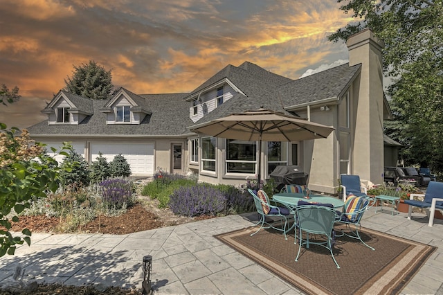 424 Saddle Ridge Rd, Hamilton, MT 59840 - rear view of property featuring stucco siding, a shingled roof, a patio area, and an attached garage