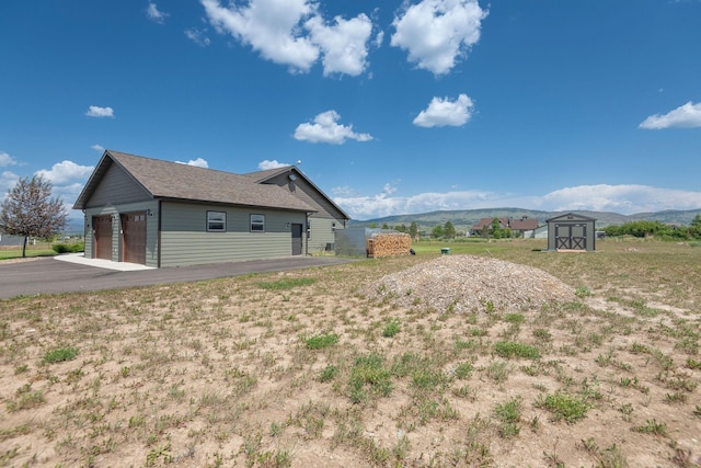 2110 Spring Wheat Loop, East Helena, MT 59635 - view of side of home with a storage unit, a garage, and a mountain view