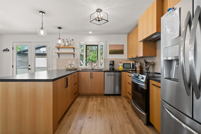 128 Mallard Loop, Whitefish, MT 59937 - kitchen featuring appliances with stainless steel finishes, a peninsula, light wood-style floors, dark countertops, and tasteful backsplash