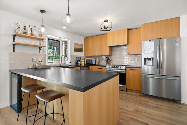 128 Mallard Loop, Whitefish, MT 59937 - kitchen with stainless steel appliances, a peninsula, light wood-type flooring, and decorative backsplash
