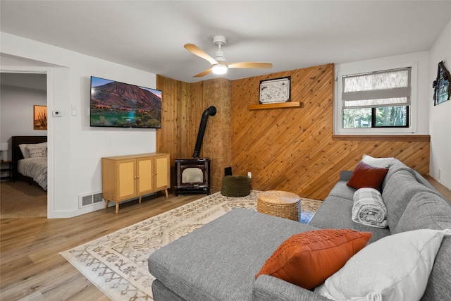 128 Mallard Loop, Whitefish, MT 59937 - living room with a wood stove, light wood-style floors, wood walls, and a ceiling fan