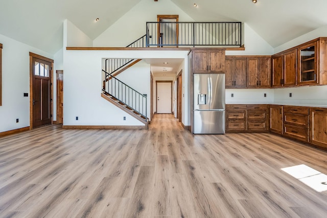 309 Stanton St, Plains, MT 59859 - kitchen featuring stainless steel refrigerator with ice dispenser, high vaulted ceiling, light wood-type flooring, glass insert cabinets, and light countertops